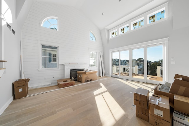 living room with high vaulted ceiling, light hardwood / wood-style floors, and a wealth of natural light