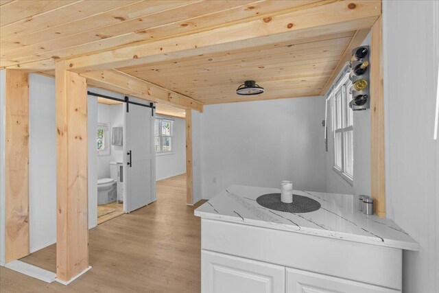 6 E Atlantic Ave, Villas, NJ 08251 - kitchen featuring wood ceiling, light stone countertops, a barn door, light wood finished floors, and white cabinetry