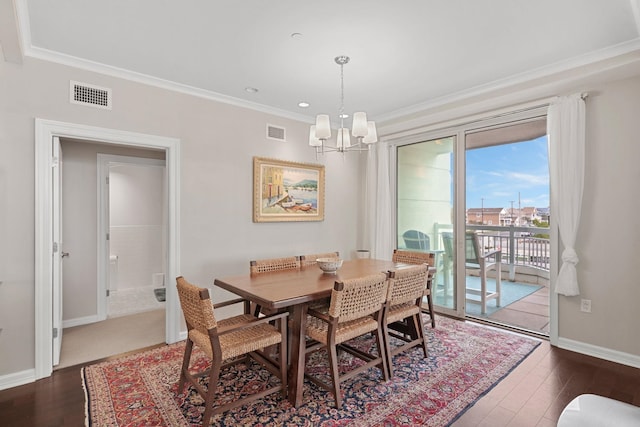 dining area featuring crown molding, dark wood-type flooring, and an inviting chandelier