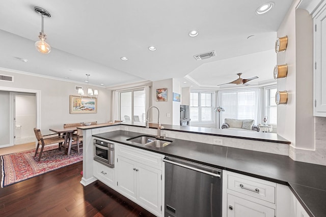 kitchen featuring pendant lighting, ceiling fan with notable chandelier, stainless steel appliances, and sink