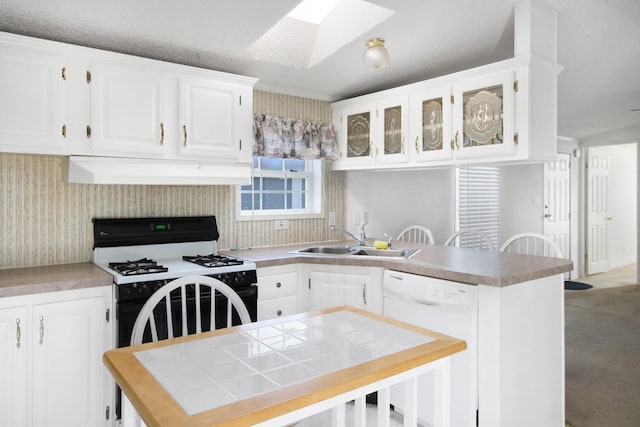 kitchen featuring a skylight, white appliances, sink, exhaust hood, and white cabinetry