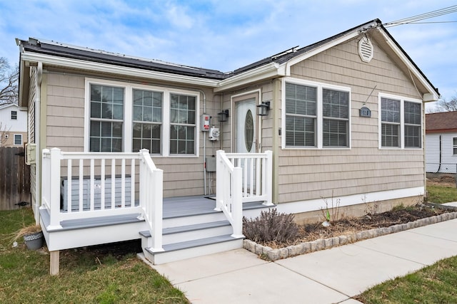 view of front of house featuring roof mounted solar panels and fence