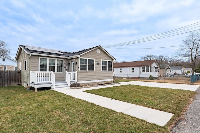 view of front of house featuring a deck, a front yard, fence, and roof mounted solar panels