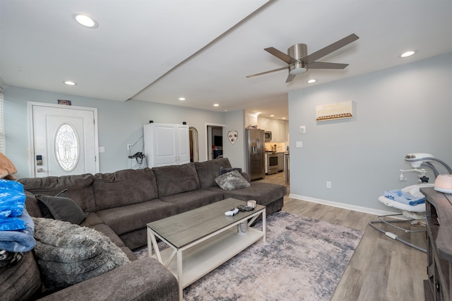 living room with baseboards, a ceiling fan, light wood-style flooring, and recessed lighting