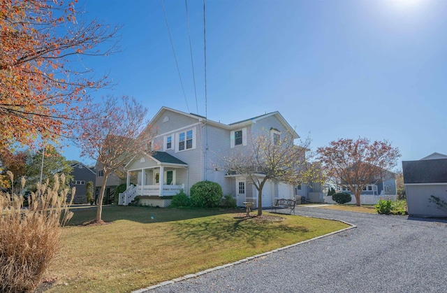 view of front of home featuring covered porch, a garage, and a front lawn