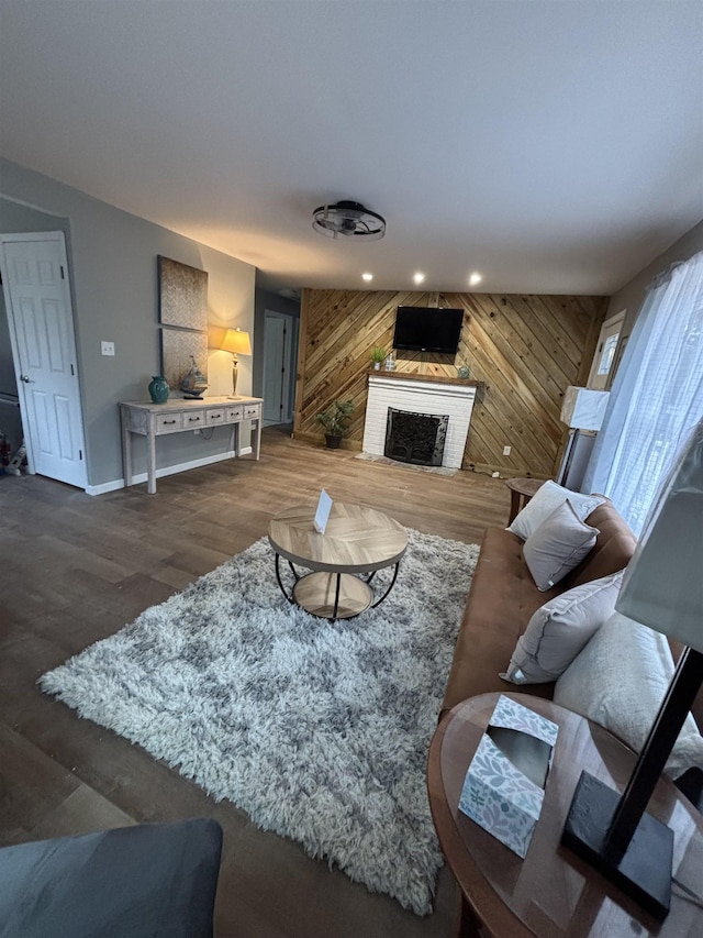 living area with a fireplace, wood walls, and wood finished floors