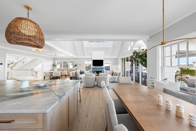 dining area featuring crown molding, lofted ceiling with beams, and light hardwood / wood-style floors