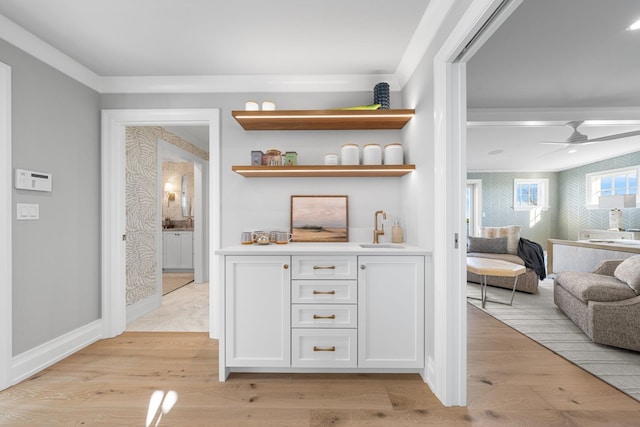 bar featuring white cabinets, sink, ceiling fan, ornamental molding, and light hardwood / wood-style floors