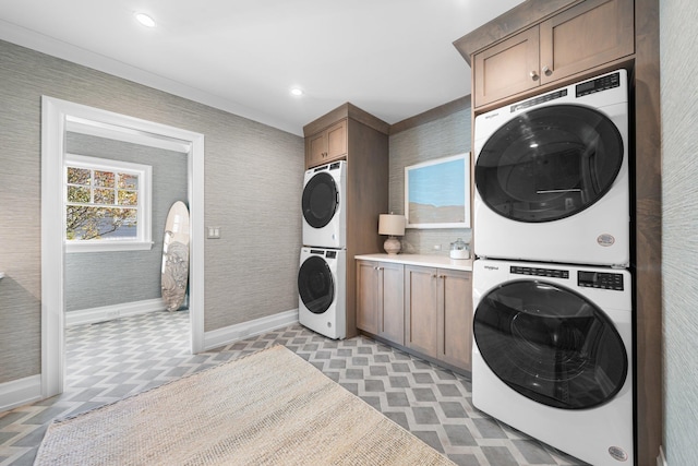 washroom featuring cabinets, stacked washer and clothes dryer, and ornamental molding