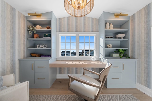 office featuring built in shelves, a chandelier, and light hardwood / wood-style flooring