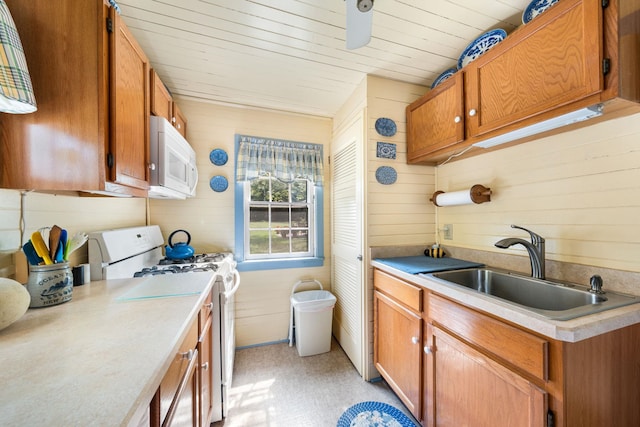 2320 Shore Rd, Ocean View, NJ 08210 - kitchen with white appliances, a sink, wooden walls, brown cabinets, and light countertops