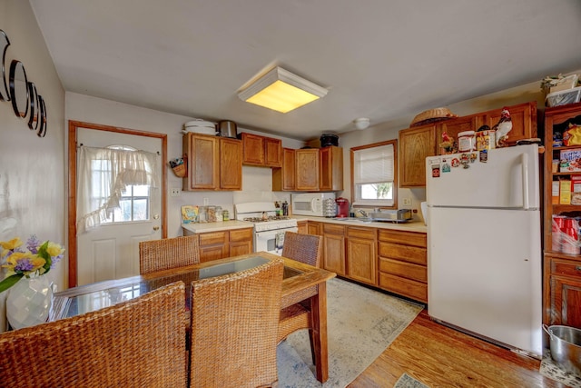 kitchen with white appliances and light hardwood / wood-style flooring