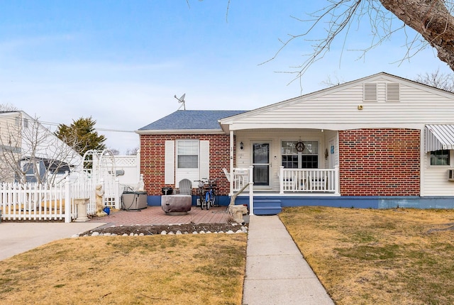 bungalow-style home featuring brick siding, a porch, a front yard, and fence