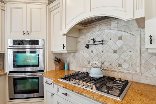 148 W Heather Rd Unit 148, Wildwood Crest, NJ 08260 - kitchen featuring stainless steel appliances, backsplash, light stone countertops, arched walkways, and white cabinetry