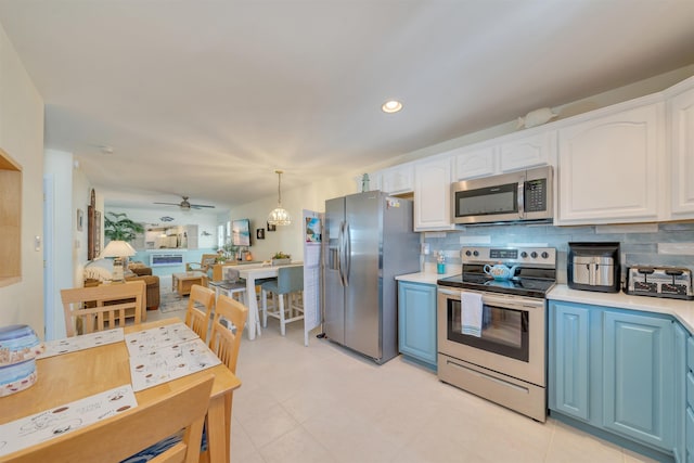 kitchen with stainless steel appliances, hanging light fixtures, light countertops, and white cabinetry