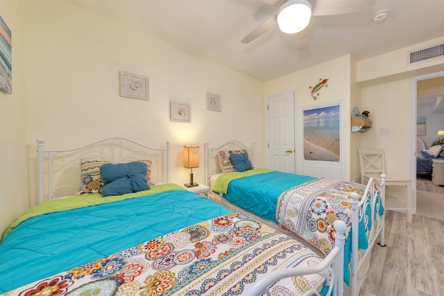 bedroom featuring a ceiling fan, visible vents, and light wood finished floors