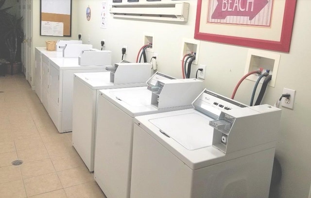 common laundry area featuring an AC wall unit, light tile patterned flooring, and separate washer and dryer