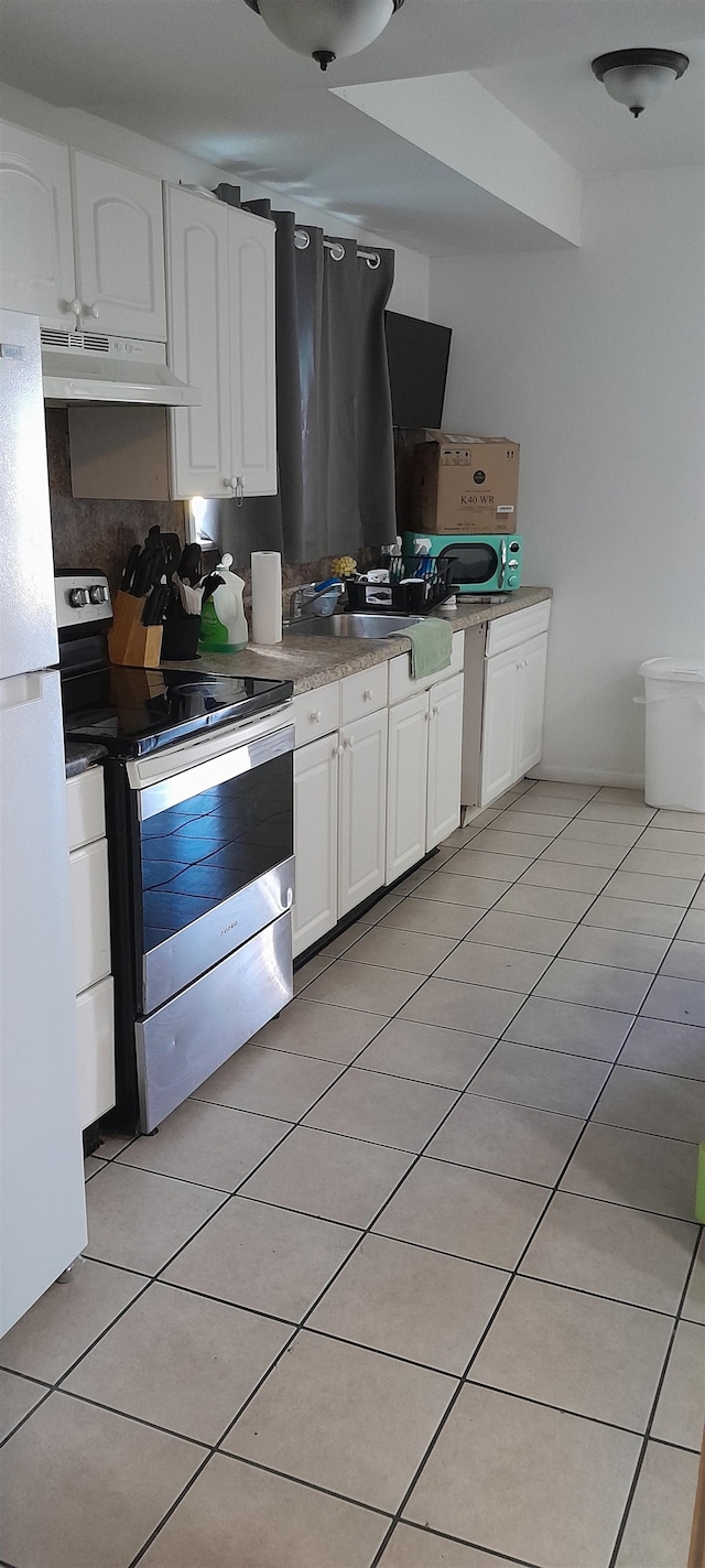 kitchen featuring stainless steel electric range, white refrigerator, and white cabinetry