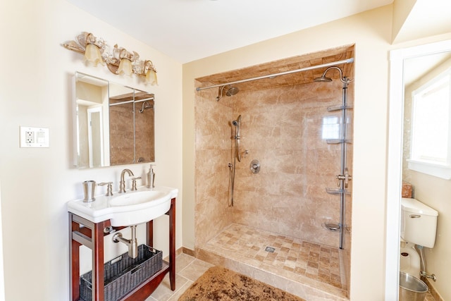 bathroom with toilet, a tile shower, and tile patterned floors