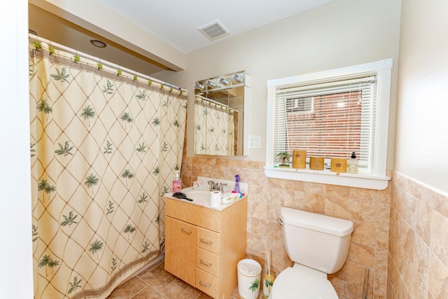 bathroom featuring tile patterned floors, vanity, toilet, and tile walls