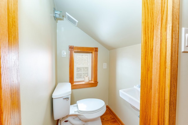 bathroom with wood-type flooring, vaulted ceiling, and toilet