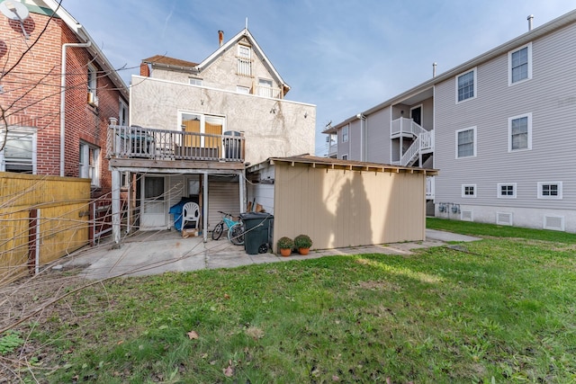 back of property with a shed, a wooden deck, and a lawn