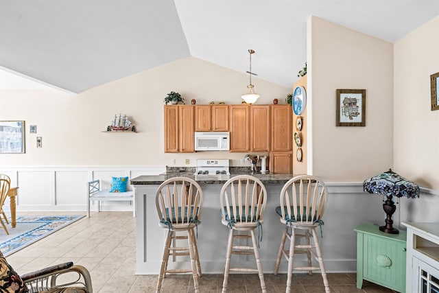 216 E Roberts Ave Unit 7, Wildwood, NJ 08260 - kitchen featuring white appliances, a kitchen breakfast bar, vaulted ceiling, light tile patterned flooring, and a wainscoted wall
