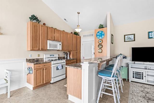 216 E Roberts Ave Unit 7, Wildwood, NJ 08260 - kitchen with white appliances, vaulted ceiling, a peninsula, a breakfast bar area, and light tile patterned flooring