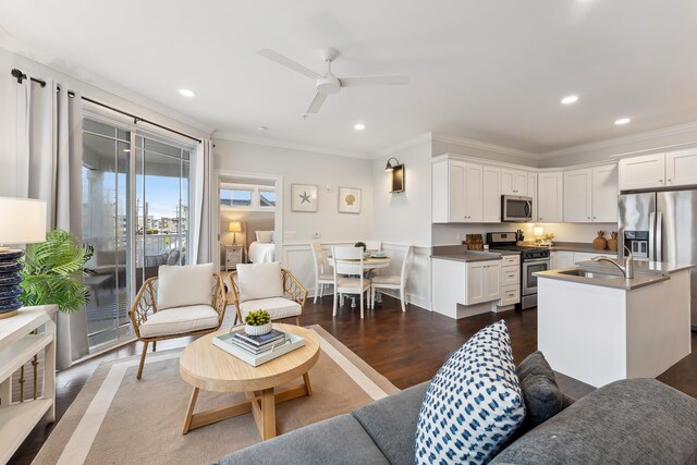 kitchen with appliances with stainless steel finishes, sink, white cabinetry, and a kitchen island with sink