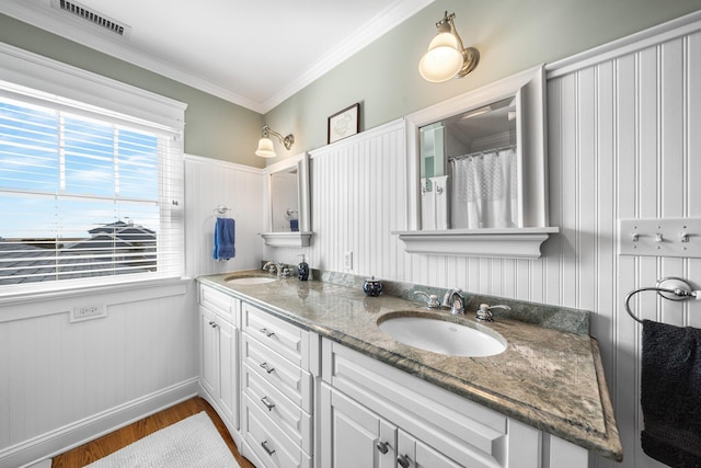 bathroom with visible vents, ornamental molding, a sink, wood finished floors, and double vanity