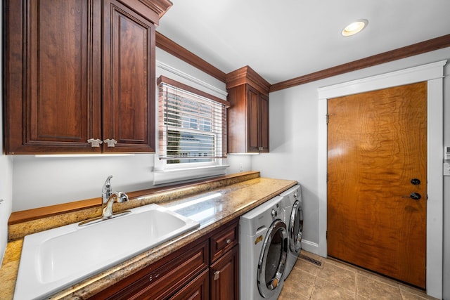 laundry area featuring cabinet space, ornamental molding, washing machine and dryer, and a sink