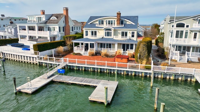 rear view of house featuring a water view, a residential view, and a chimney