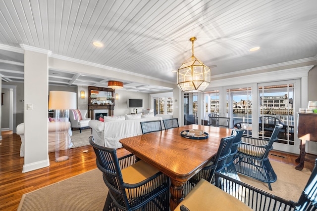 dining area with coffered ceiling, wood finished floors, a fireplace, and crown molding