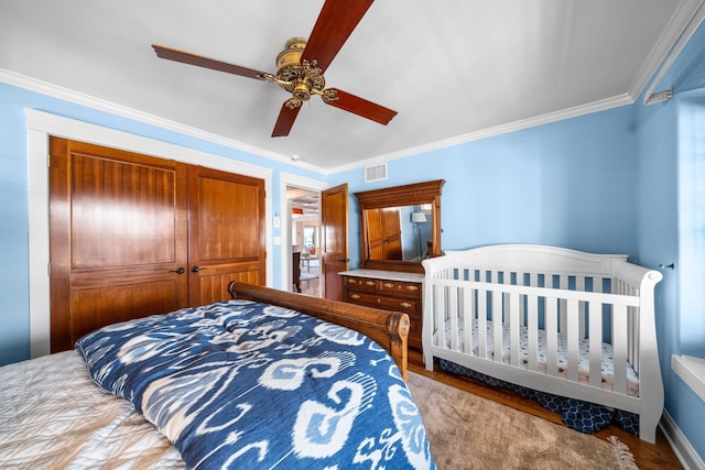 bedroom featuring visible vents, ornamental molding, wood finished floors, a closet, and ceiling fan