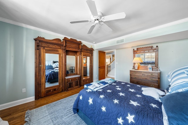 bedroom featuring visible vents, crown molding, baseboards, and wood finished floors