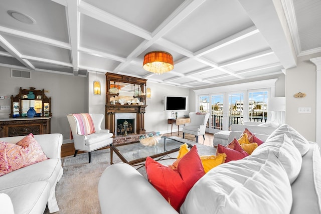 living room featuring beam ceiling, visible vents, a fireplace with raised hearth, and coffered ceiling