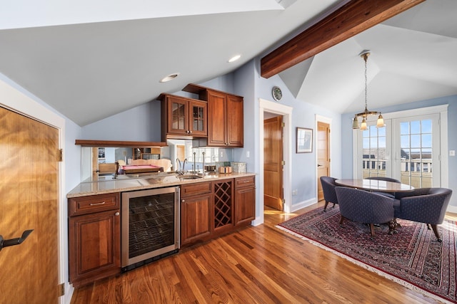 kitchen with beverage cooler, dark wood finished floors, vaulted ceiling with beams, glass insert cabinets, and brown cabinets