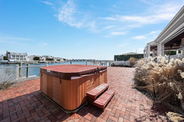 view of patio / terrace with a water view, a ceiling fan, and a hot tub