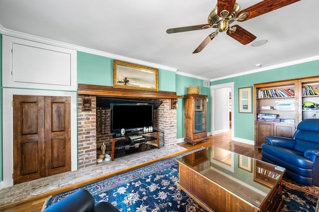 living area featuring wood finished floors, baseboards, visible vents, ceiling fan, and ornamental molding