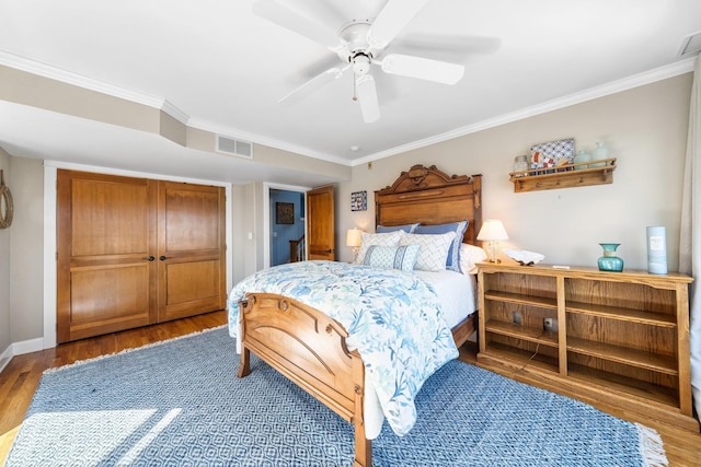 bedroom with visible vents, ornamental molding, wood finished floors, a closet, and ceiling fan