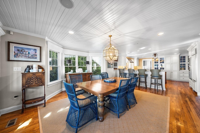 dining area featuring visible vents, crown molding, baseboards, and wood finished floors