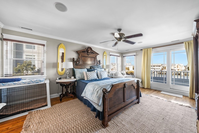 bedroom with crown molding, wood finished floors, visible vents, and baseboards