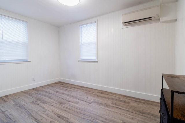 unfurnished room featuring a wall mounted air conditioner and light hardwood / wood-style floors