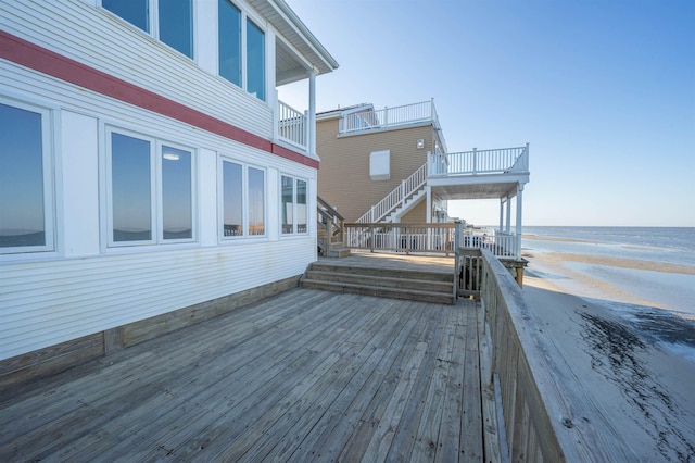 wooden deck with a water view and a beach view