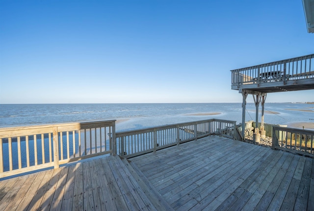 wooden terrace featuring a view of the beach and a water view