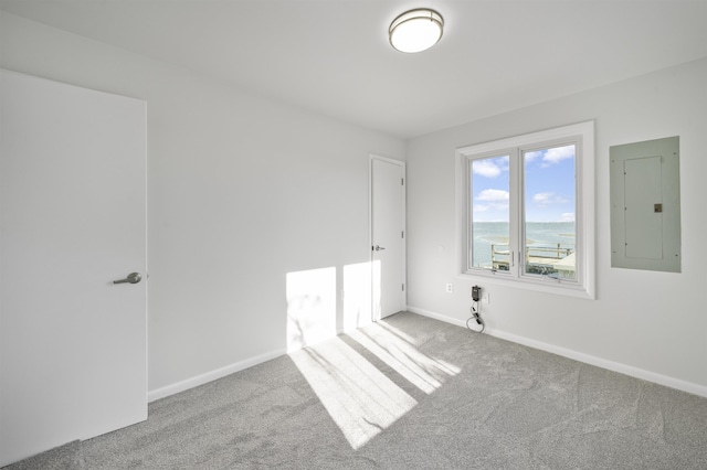 carpeted empty room featuring electric panel and a water view