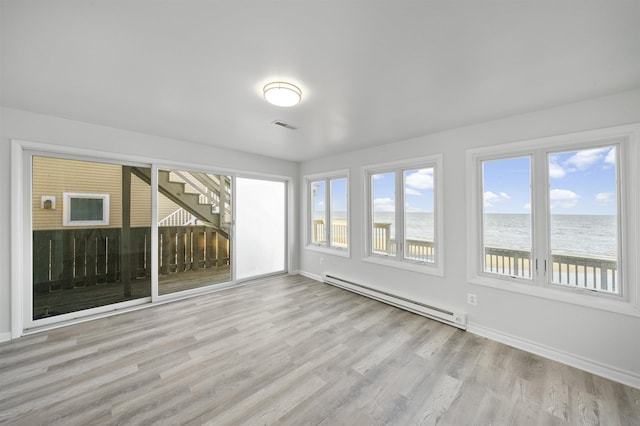 unfurnished sunroom with a beach view, a baseboard radiator, and a water view