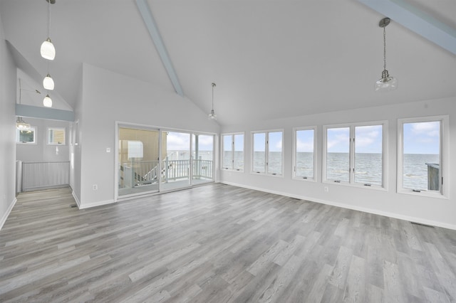 unfurnished living room with a high ceiling, light wood-type flooring, a water view, and plenty of natural light