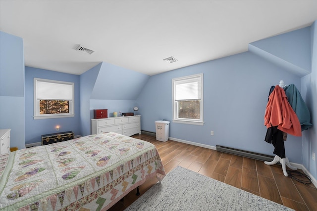 bedroom featuring a baseboard heating unit, visible vents, vaulted ceiling, and wood finished floors