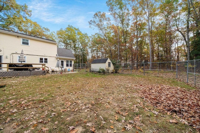 view of yard with a storage shed, a fenced backyard, a wooden deck, and an outbuilding